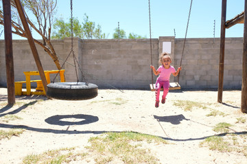 Little girl playing on playground swing