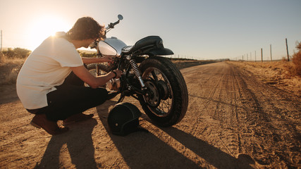 Fototapeta na wymiar Man checking his motorcycle on country road