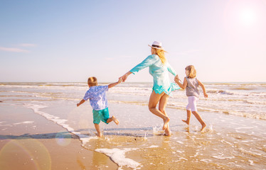 mother and children run on the shore