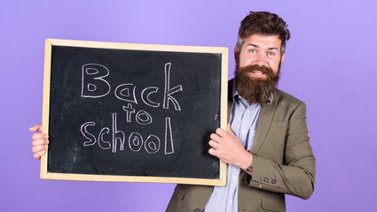 Invite to celebrate day of knowledge. Teacher advertises back to school buy new school supplies. Teacher bearded man stands and holds blackboard with inscription back to school violet background