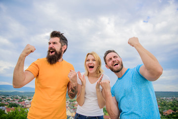 Woman and men look emotional successful celebrate victory sky background. Threesome winners happy with raised fists. We are winners. Celebrate success. Behavior successful team. Emotional explosion