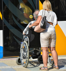 Old man in a wheelchair next to a tram