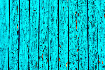 An old wooden wall painted with blue paint, the paint is peeling off