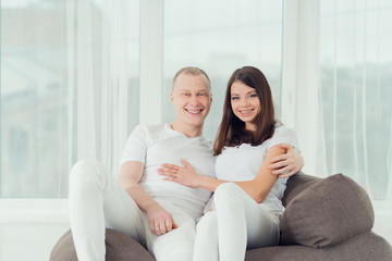 Obraz premium young happy couple in white clothes sitting in armchair, smiling