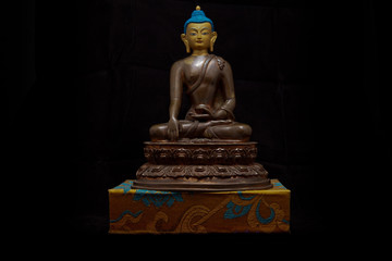 Buddhistic sculpture as a decoration on top of a book with black background