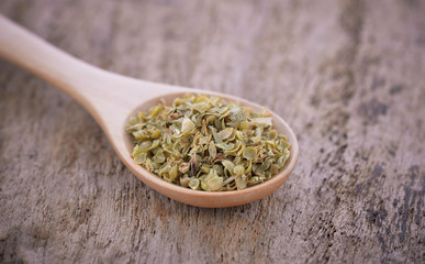 Oregano on wooden spoon isolated on wwooden background.