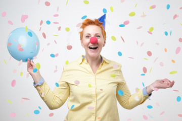 Fashion woman sends an air kiss with colorful balloons on blue background