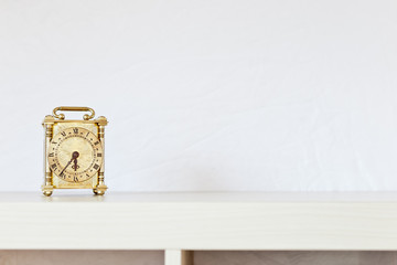 Vintage looking decorative clock on a wooden light coloured book case with white background