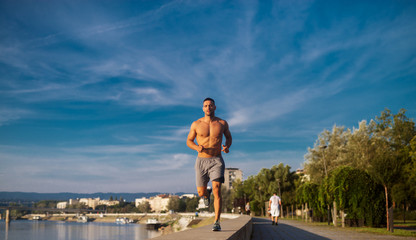 Fitness training outdoors. Handsome man working exercises in early morning with sunrise. Muscular man training outside. Sunny fitness morning.