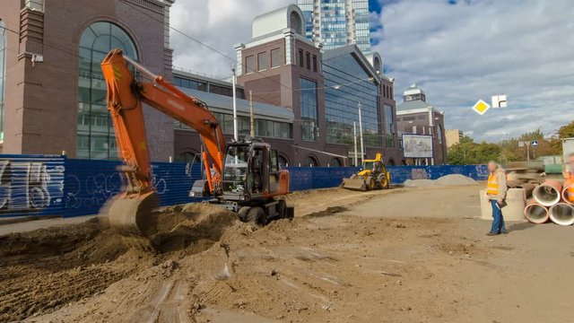 Industrial excavator loading soil material from road construction site into a dumper truck timelapse