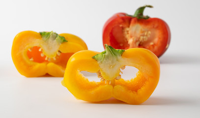 three cut peppers. two yellow and one red. presented on a light background