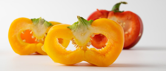 three cut peppers. two yellow and one red. presented on a light background