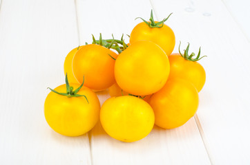 Bunch of ripe yellow tomatoes on white wooden table