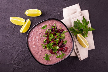 Fototapeta na wymiar Mexican red bean puree soup with lime, parsley and chilli pepper.