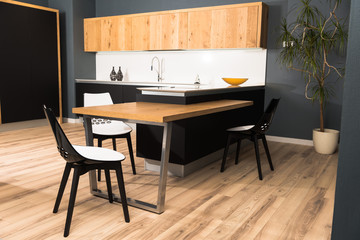 interior of modern clean light kitchen with comfortable furniture and potted plant
