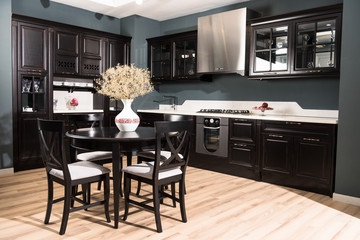 interior of modern kitchen and dining room with black wooden furniture and vase of dried flowers on table