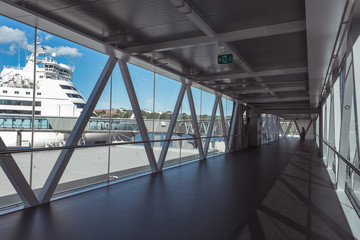 International ship terminal of the largest port in Stockholm. The way to a large tourist liner. Tunnel for tourists and passengers. View of a white ship through panoramic windows.