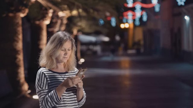 woman in the street of a night city with an electronic device