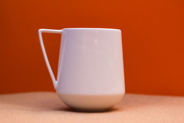 White ceramic cup against orange background