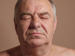 Aged man portrait on light background.