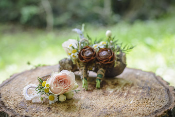 weeding boutonnieres with rose and pine cone on a wooden stump.
