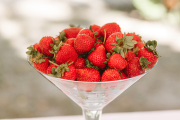 Fresh juicy strawberries in martini glass. Blurred background with homespun napkin. Side view. Place for text
