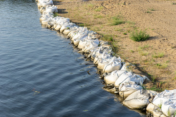Obraz premium flood safety or protection sand bags at a river shore line