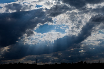 Dramatic cloud formation in the blue sky with light beams coming through forming Jacobs ladders