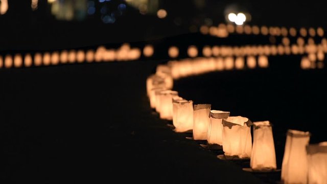 Christmas Eve night candle lights paper bags flickering, glowing along road illuminated by houses in residential neighborhood in Burke, Virginia