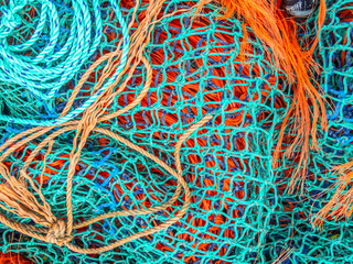 Layers of blue and orange fishing nets and ropes slightly frayed in places