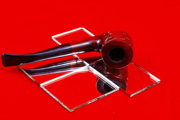 Smoking tubes, a violin and a mirror on a red background.