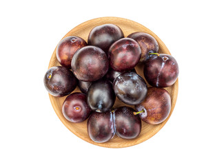 Wooden bowl with ripe plums on white. Top view.