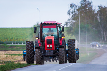 Agricultural tractor moving on the asphalt road after working in field