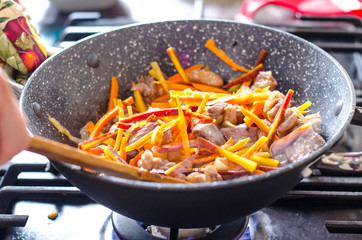 Meat with vegetables in frying pan wok on stove