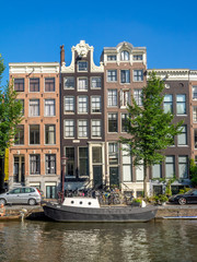 Amsterdam canal, bridge and typical houses, boats and bicycles during the day, Holland, Netherlands.