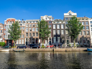Fototapeta premium Amsterdam canal, bridge and typical houses, boats and bicycles during the day, Holland, Netherlands.
