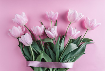 Bouquet of pink tulips flowers over light pink background. Greeting card or wedding invitation. Flat lay, top view, copy space.