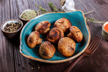 Baked champignons mushrooms with butter, spices on wooden background. Healthy food concept. Georgian cuisine. Top view