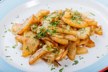 Roasted potato with herbs on plate on dark wooden background with fork, homemade food. Top view