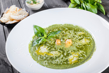French soup with seafood, shrimp, cheese parmesan, herbs and lemon on plate on dark wooden background. Thai traditional food