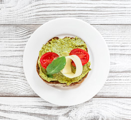 Breakfast sandwich with avocado, tomatoes, cheese parmesan on plate on wooden background. Healthy snack and appetizer