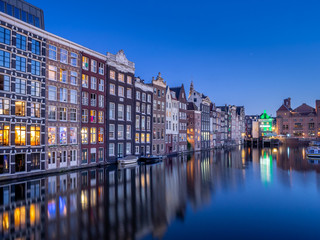 Historic buildings on the Damrak canal in the centre of beautiful Amsterdam at night.