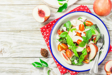Peach tomato basil salad on white rustic background. Top view, space for text.
