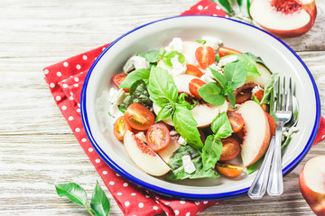 Peach tomato basil salad on white rustic background. Top view, space for text.