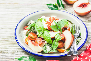 Peach tomato basil salad on white rustic background. Top view, space for text.