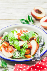 Peach tomato basil salad on white rustic background. Top view, space for text.