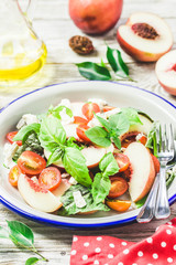 Peach tomato basil salad on white rustic background. Top view, space for text.