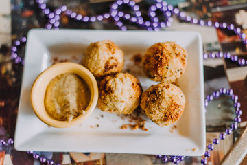 Cajun appetizer on table surrounded by beads. House made boudin balls and creole mustard.