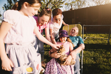 Proud grandparents are sitting and playing with their cute grandchildren in backyard.