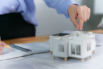 Female designer ,Architect holding a home model in loft modern office. Architectural project concept. University student planning engineering design at workplace.